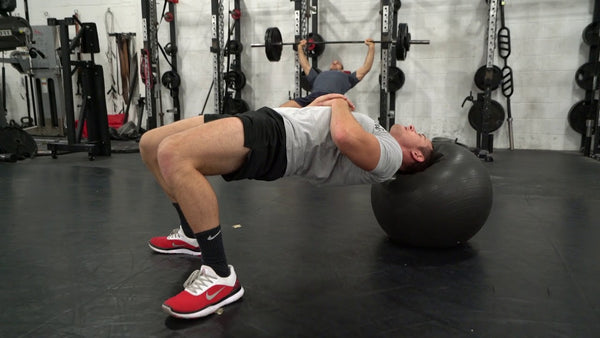 Athlete doing a neck plank on a grey exercise ball