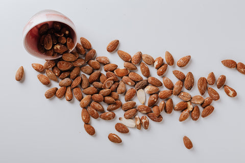 Almonds spilling out from a bowl onto a table