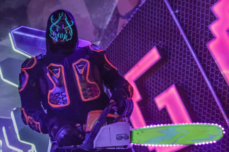 Neon Masked Man Holding A Chainsaw