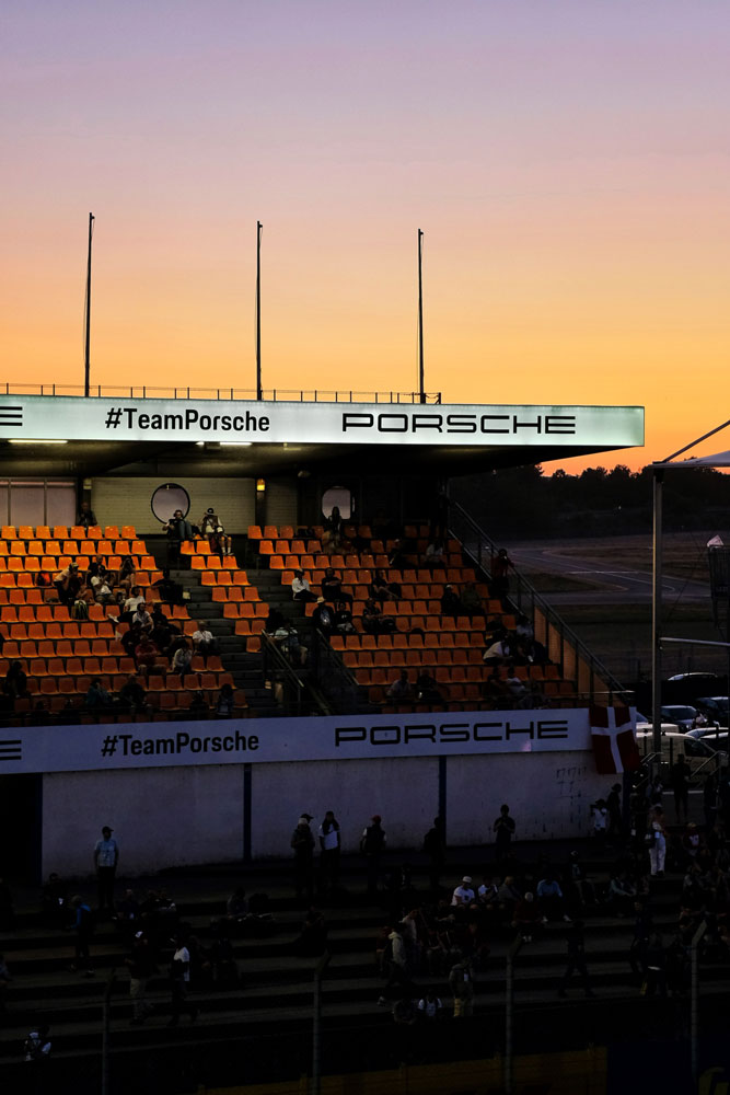 24th Hours Of Le Mans, spectators watching the race from the stands while the night approaches and the cars starts turning lights for the night race and the circuit in France becomes completely dark.