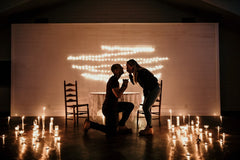Man proposing to girlfriend with candles all around them