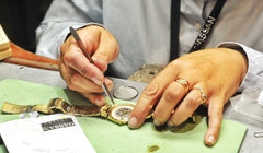 Man doing repairs on the back of a gold watch