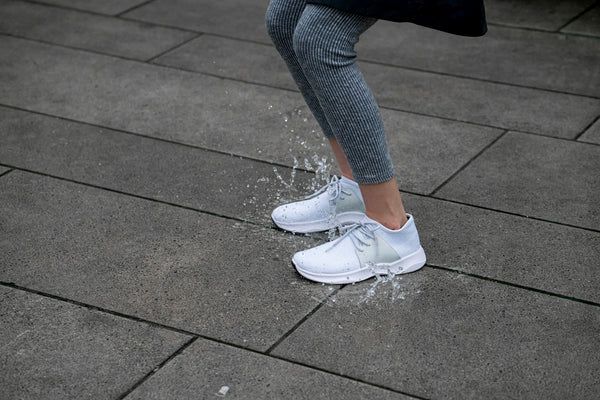 Person wearing Vessi rain shoes jumping on a puddle