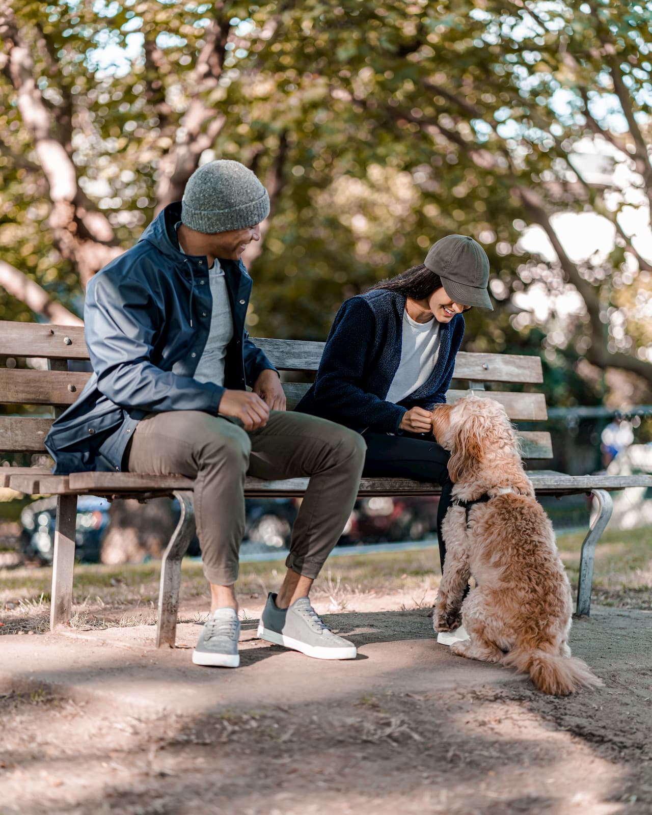 Man and woman sitting on a bench with their fluffy dog in the fall.