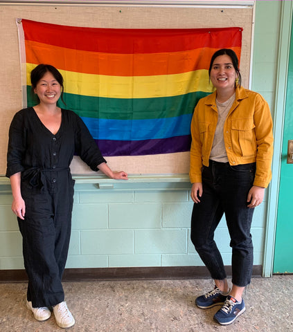 Two teachers in front of Pride flag