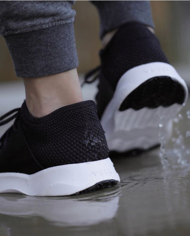 Close image of a woman’s feet in comfortable shoes walking on a watery path