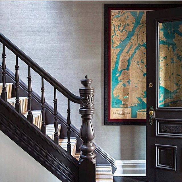 .Side view of entrance stairway with dark wood banister. Nautical map and textured grasscloth on wall.