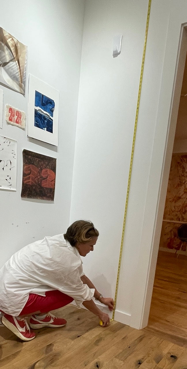 Person showing how to measure height of wall for wallpaper using a tape measure
