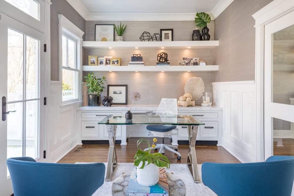 Soft lit home office with pale gray grasscloth walls and shelves with objects