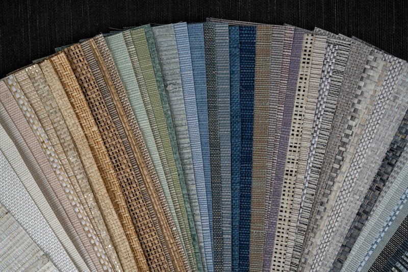 A fanned-out assortment of textured, colorful grasscloth wallpapers.