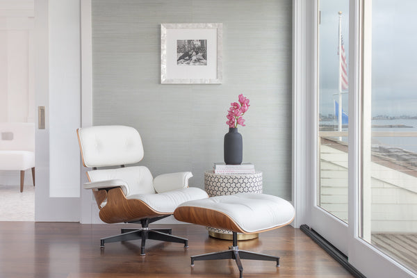 Modern living room featuring spring decor ideas with a white leather chair and ottoman, against a textured pale blue grasscloth wall.