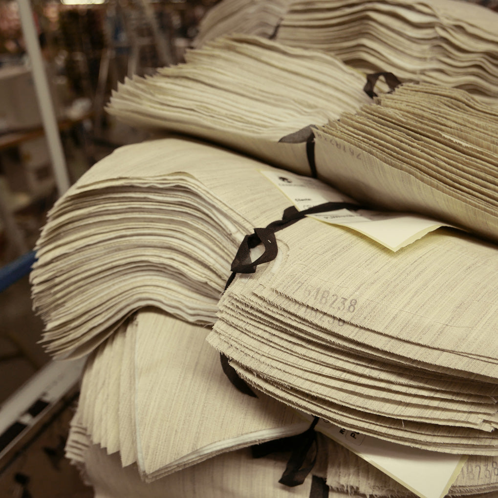 A large stack of pre-cut suit canvas waiting to be placed in a jacket..