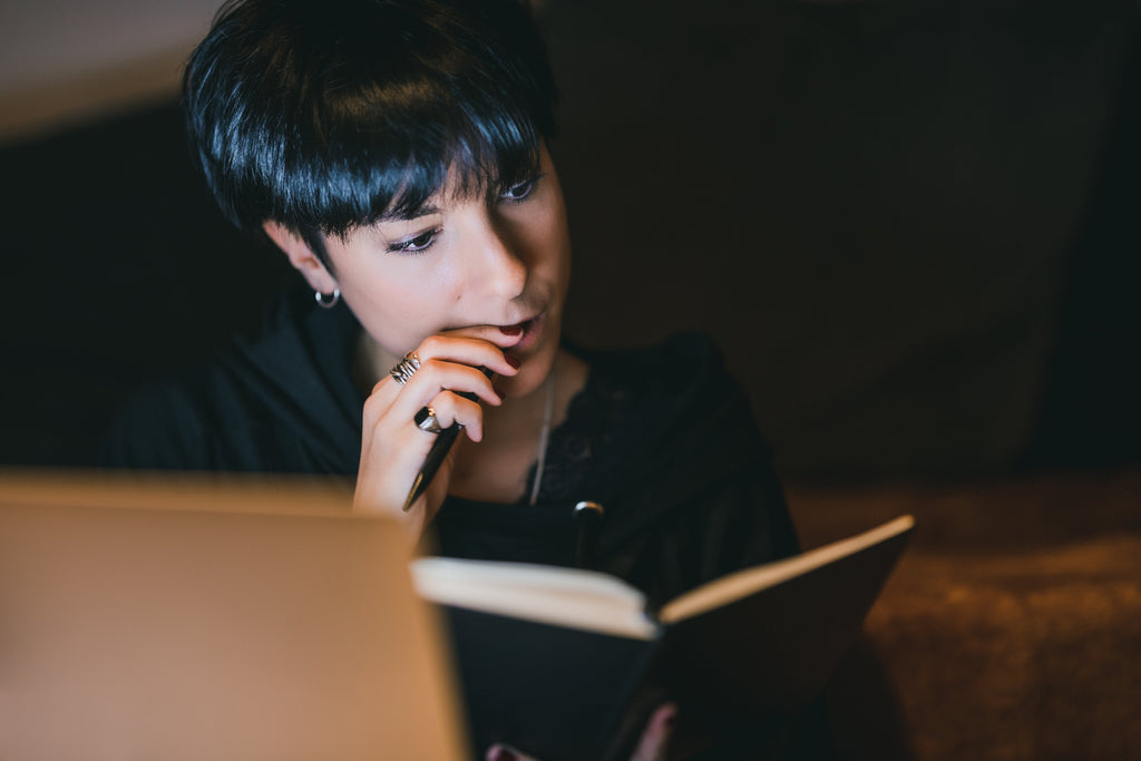 person-bites-the-back-of-a-pen-as-they-look-at-an-open-notebook-thinking-who-should-avoid-or-not-do-yoga