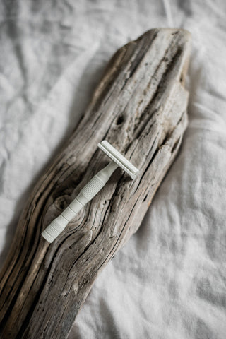 white safety razor on wooden log