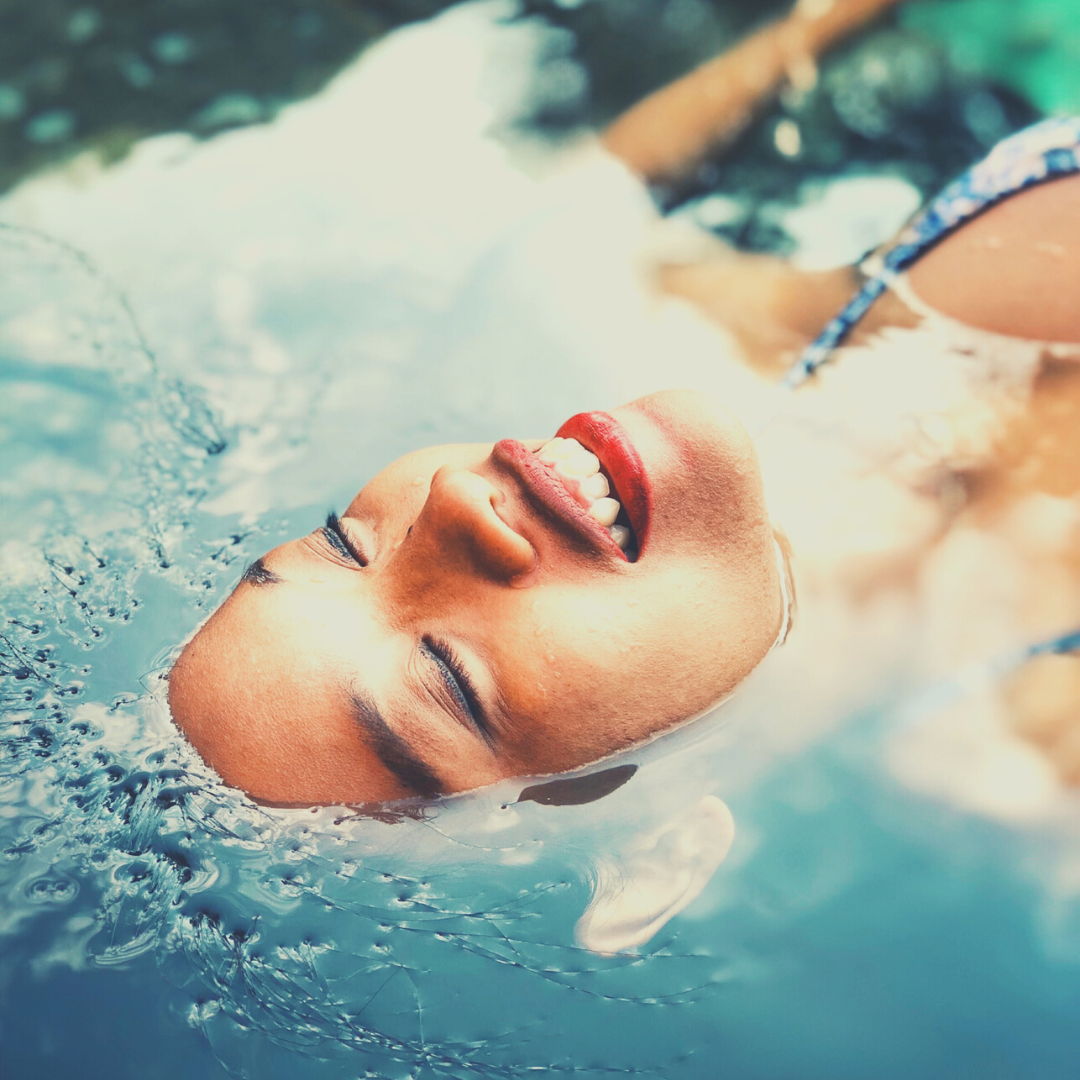 Black woman floating in the water, looking peaceful with her eyes closed