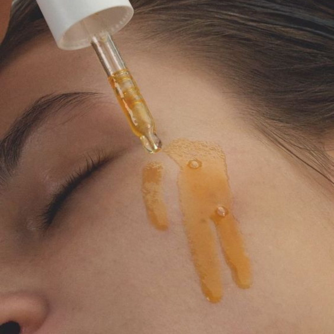 close of of woman's face with orange vitamin c serum being applied with a dropper