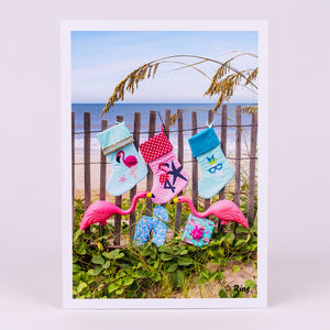 Christmas Notecard with 3 Stockings and Yard Flamingos on Dunes Fence on Beach
