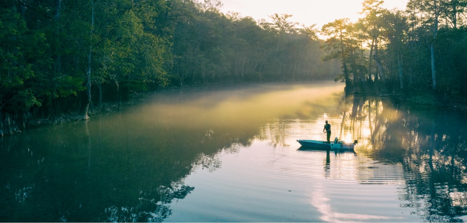 Man stands and fishes from his LONO Aero inflatable kayak in the early sunrise.