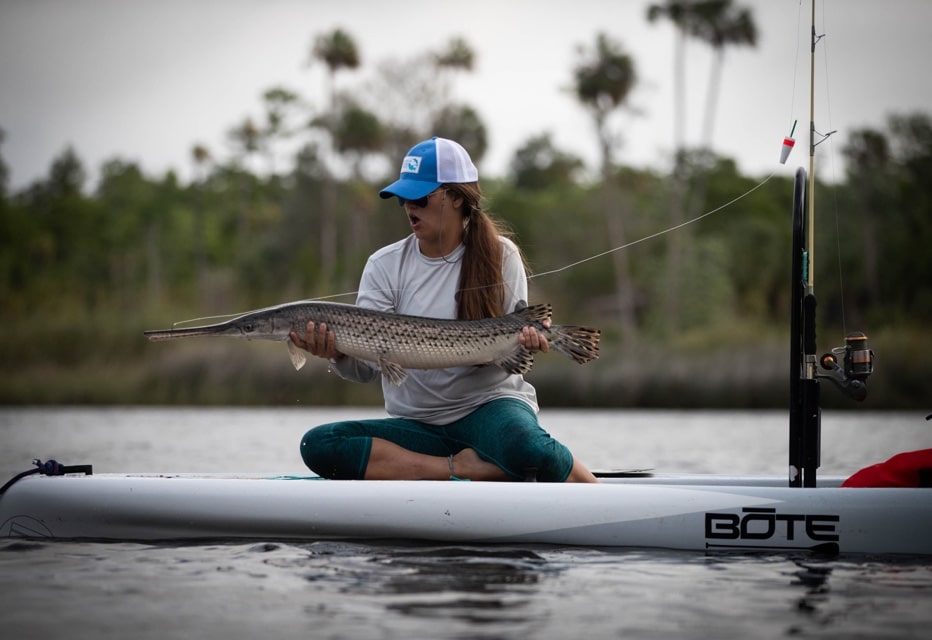 woman catches large gar fish on BOTE paddle board