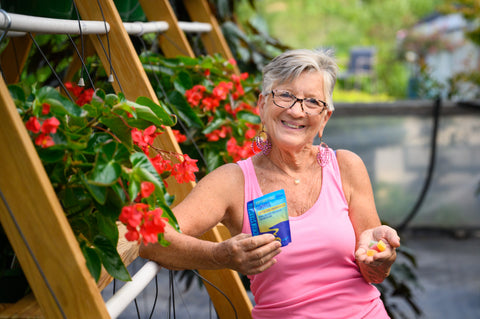 Mrs. Susie in the greenhouse holding Appalachian Standard hemp gummies