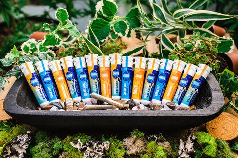 Pre rolls laid among plants in a wooden bowl surrounded by plants