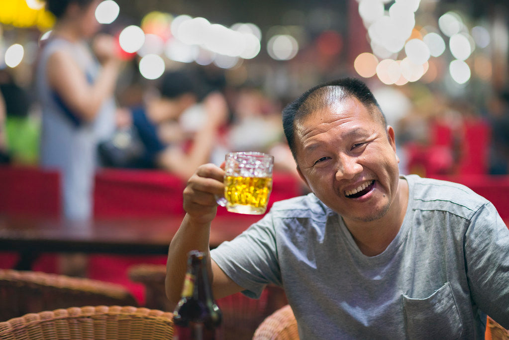 Asiatischer Mann hebt Bierglas