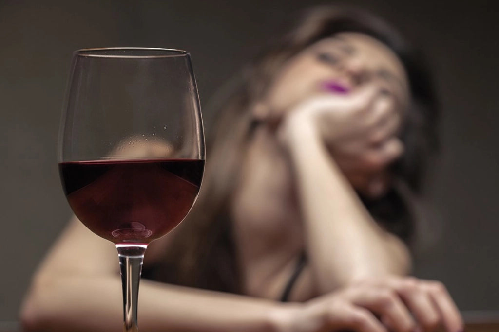 Betäubte Frau mit einem Glas Wein