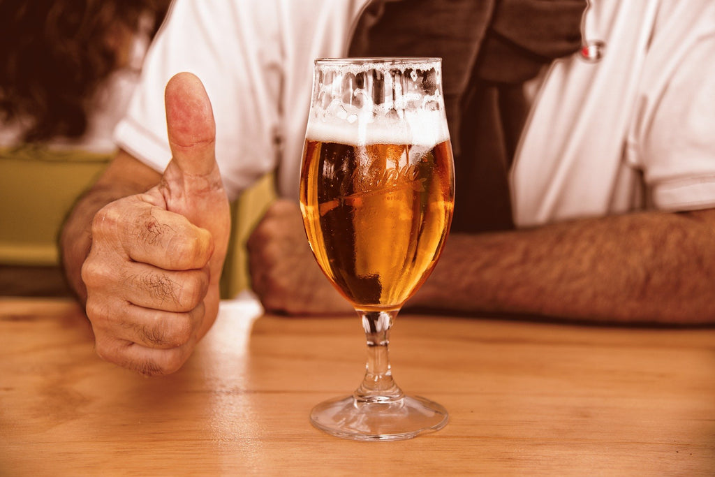 Mann zeigt Daumen hoch neben einem Bierglas