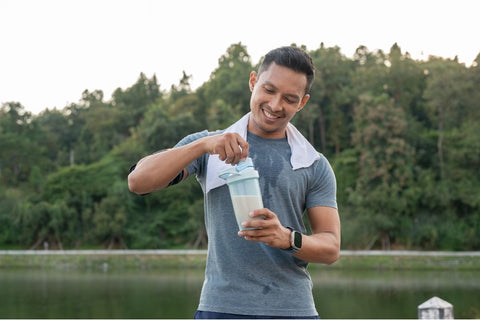 A person drinking a meal replacement shake in their kitchen.