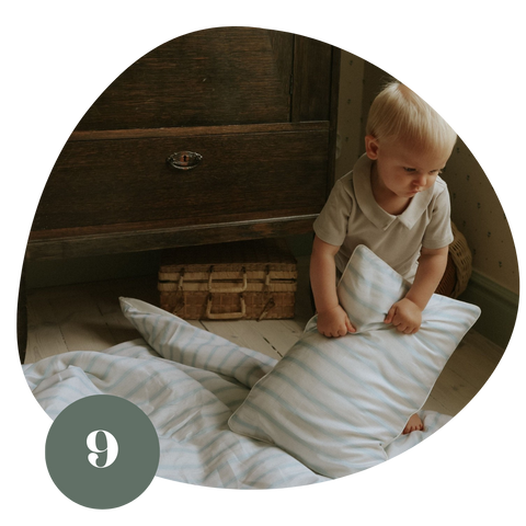 Little boy moving a blue and white striped pillow