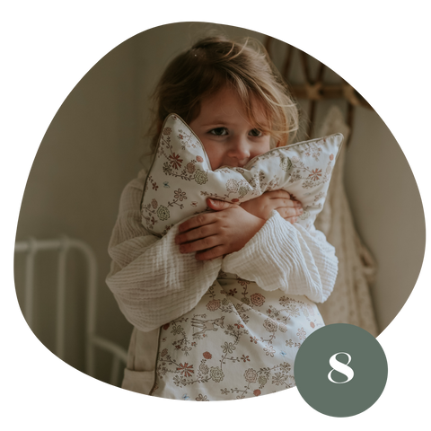 Toddler girl holding a pink pillow with flowers and deer printed on it