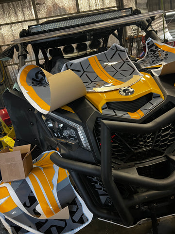 Custom wrap being installed on a CanAm Maverick X3