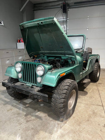 A Jeep CJ6 sits with the hood popped open