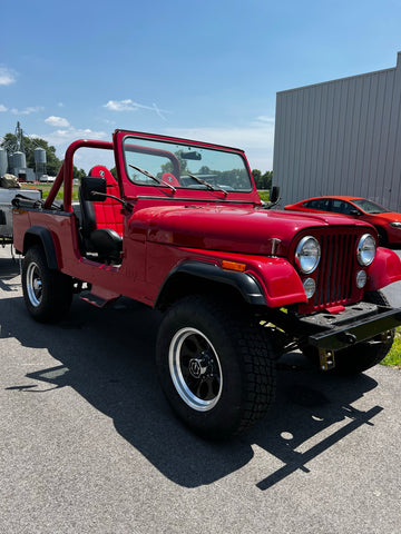 Another Jeep Scrambler CJ8 sits outside the shop