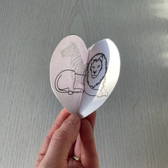 Two paper hearts slotted together to make up a 3D heart featuring an illustration of a lion from the black and white book project