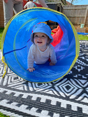 toddler crawling through a play tunnel