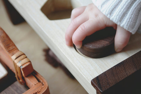 baby hand on top of wooden toy
