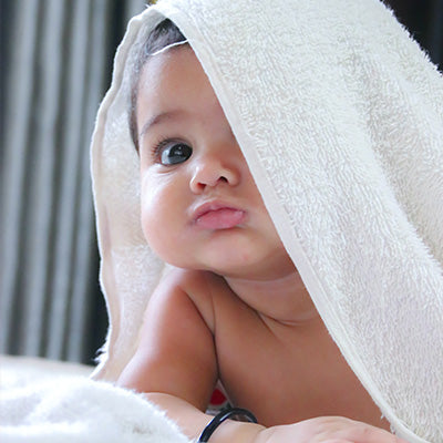 Baby peeks out from under baby bath towel