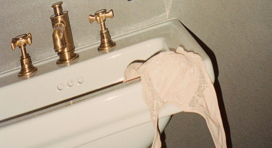 Pink Lacy Bra Hanging to dry off edge of bathroom sink