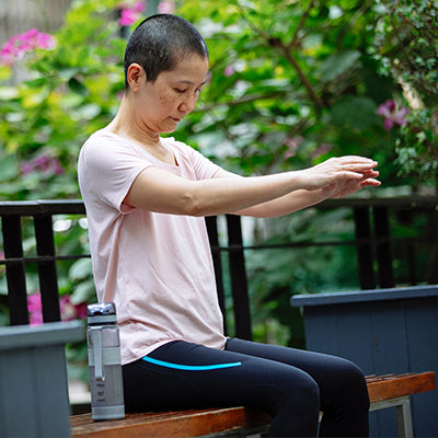 Woman gently stretches outdoors, following mastectomy