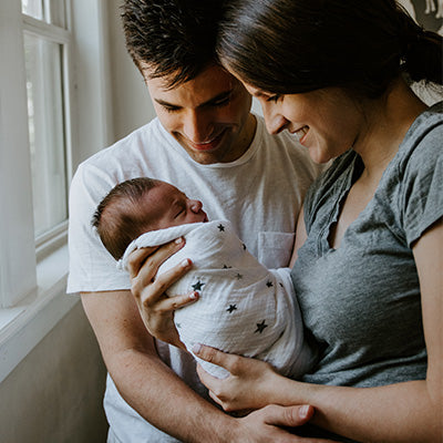 Mother and father gently cradle newborn baby in swaddle