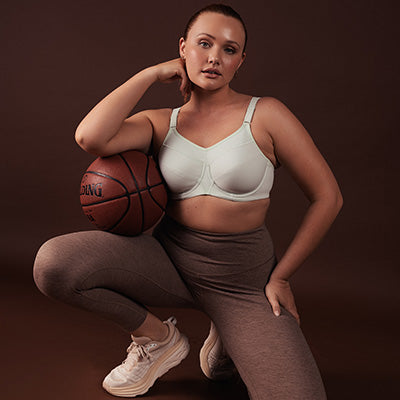 Brooke wears green Ultra Sports Bra while kneeling with basketball