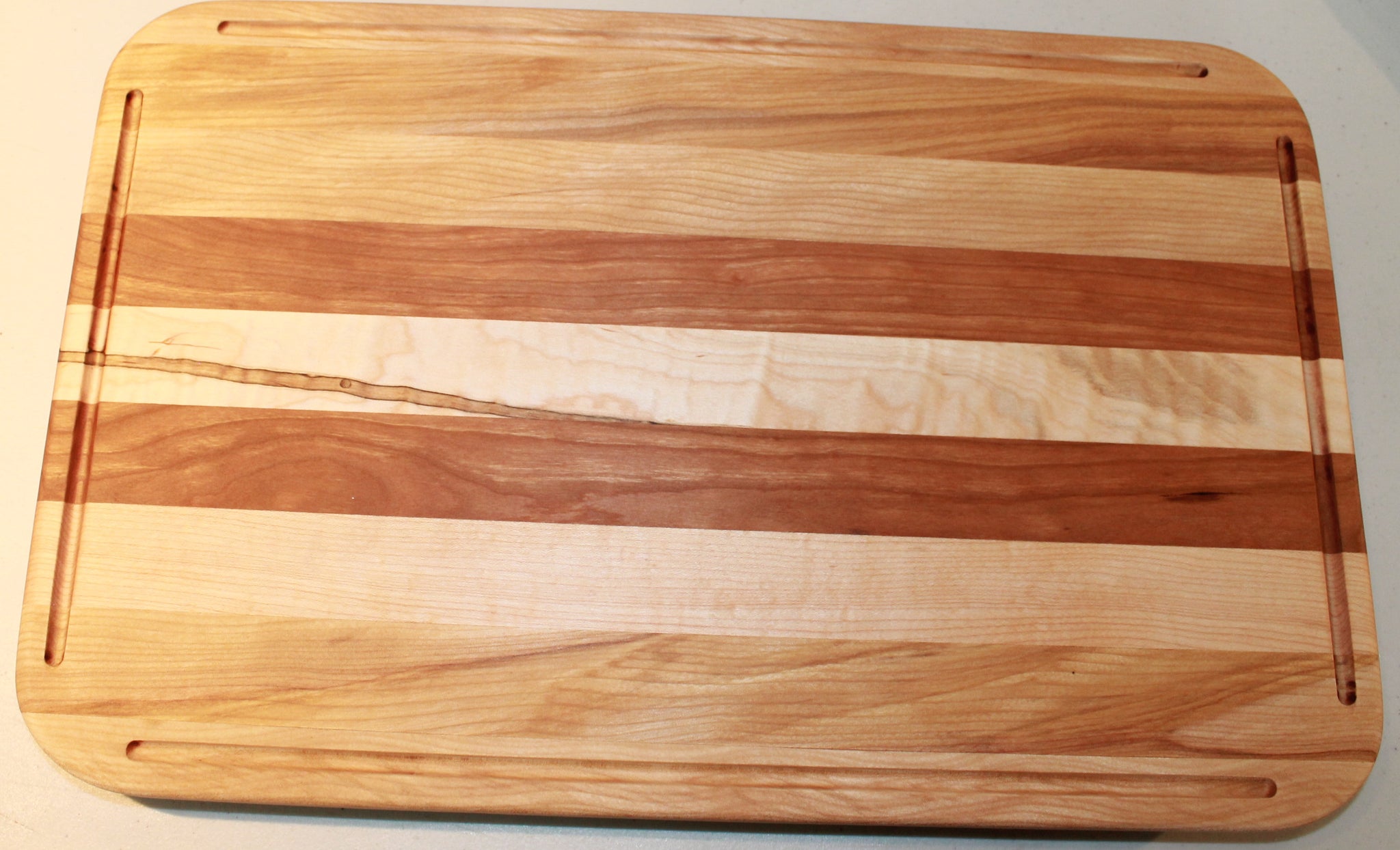 Square cutting board with rounded edges; light wood.