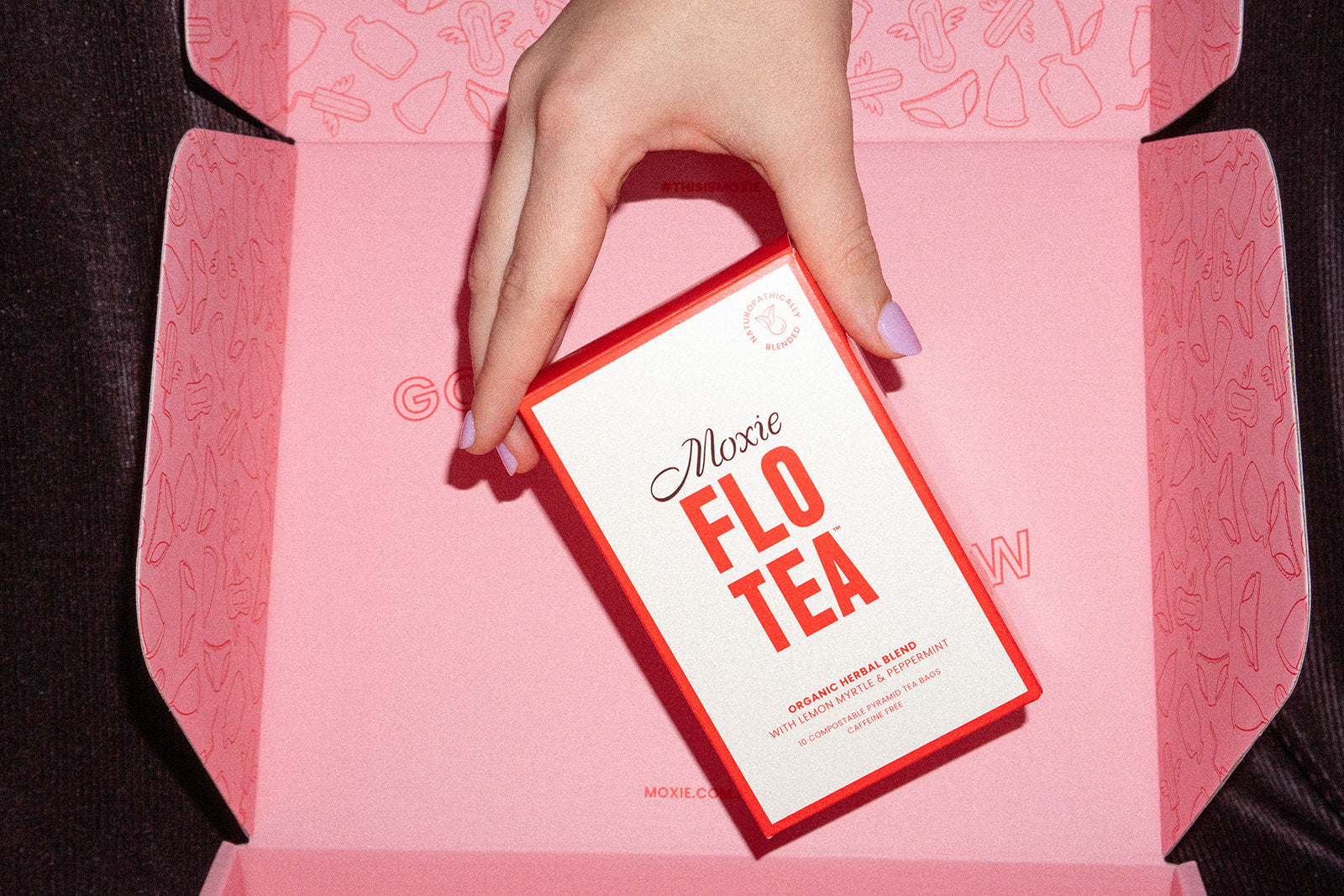 Hand holding a Moxie FLO TEA white and red pack