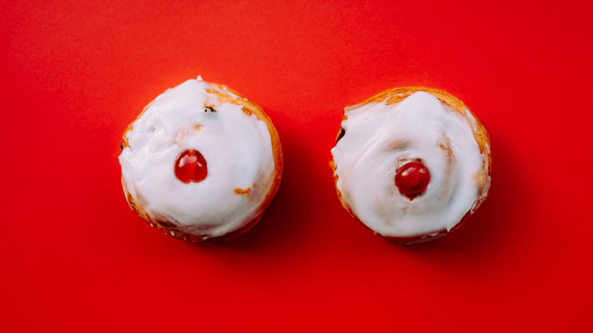 Photo of iced cupcakes with glazed cherry on each, on a red background