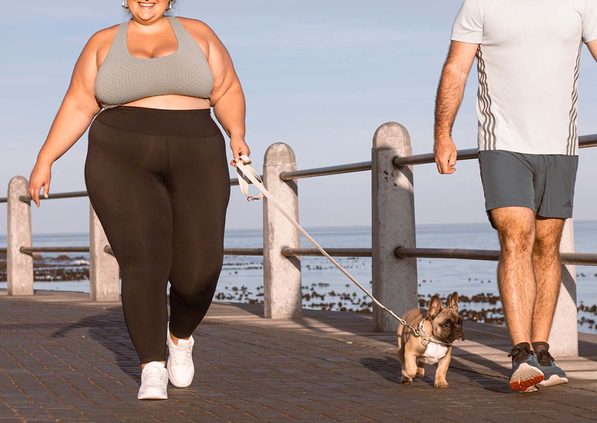 Valgray for Dogs designers dog collars and leashes based in Cape Town, South Africa blog on seven ways to show your dogs you love them and making time for daily dog walks. Image shows a French bulldog and body-positive owners taking a walk on the beachfront. The French bulldog dog is wearing a Valgray for Dogs tear-resistant, waterproof dog collar and leash set with personalised name tags.