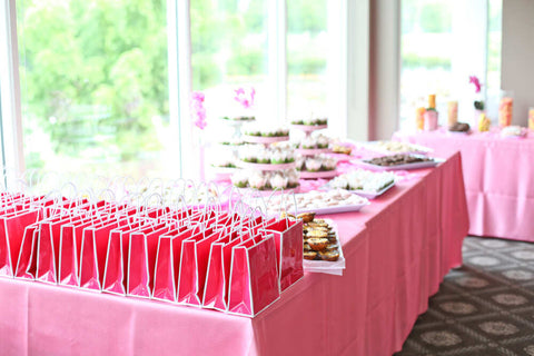 Rows or pink party favor bags on a table