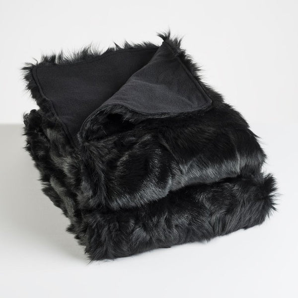 Luxurious real black fur blanket with cashmere wool lining lying neatly folded with a white background