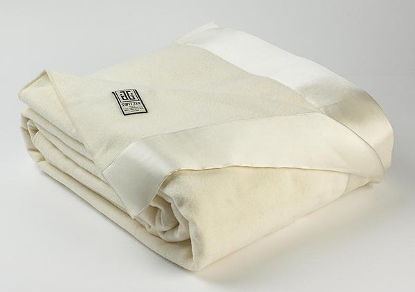 Photo of Henry luxury blanket and throw in white with shining silk borders lying neatly folded.