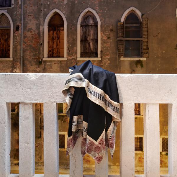 Now Voyager luxury travel throw blanket in black hanging on a scenic balcony during a travel to Venice